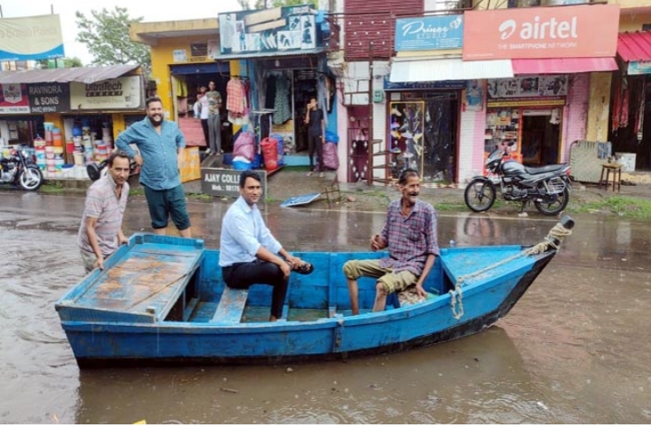 डाडासीबा बाजार में बारिश के बाद जलभराव, दुकानदारों ने नाव चलाकर जताया विरोध